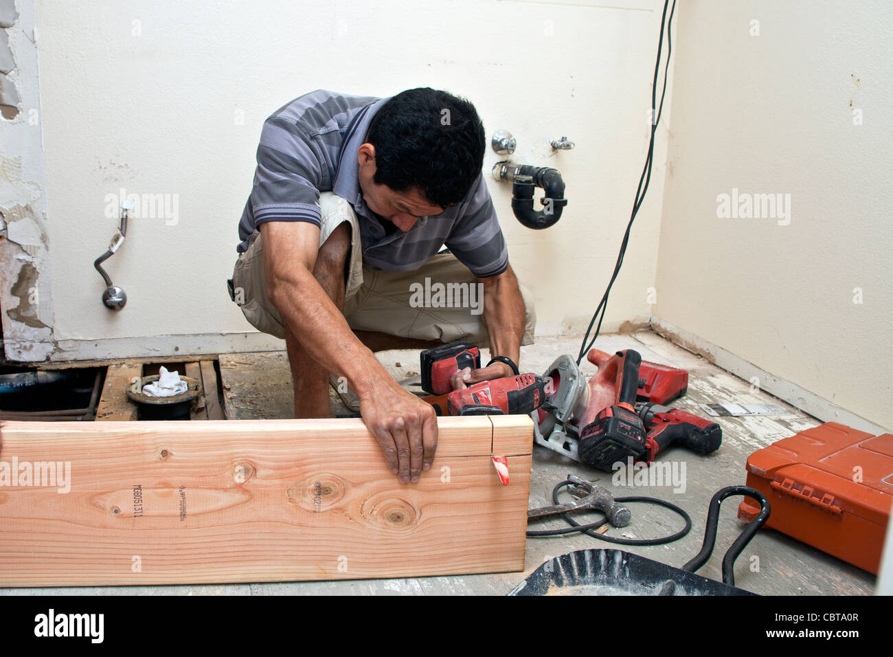 Uomo ispanico dal Messico il suo lavoro di costruzione business negli USA sostituisce la trave di supporto al piano di sopra bagno signor © Myrleen Pearson Foto Stock