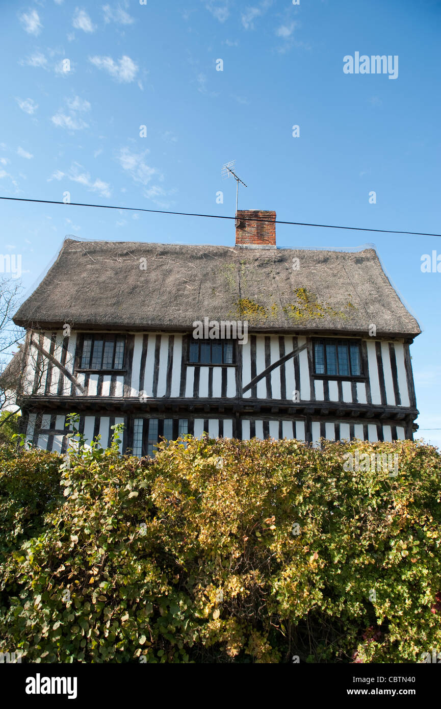 Un vecchio con il tetto di paglia di legno casa in campagna britannica con una siepe Foto Stock