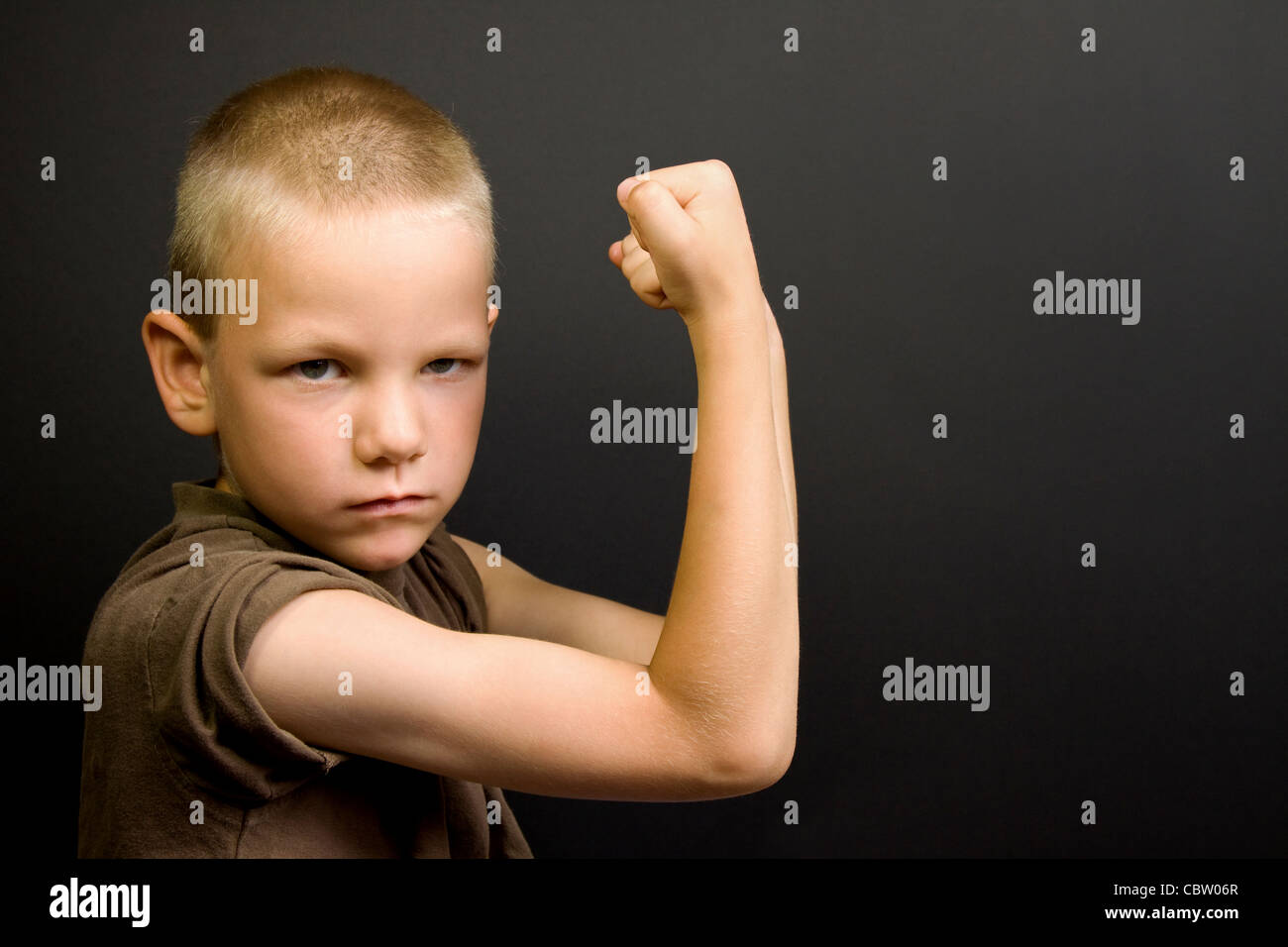 Giovane ragazzo flettendo i suoi muscoli e la ricerca dura Foto Stock
