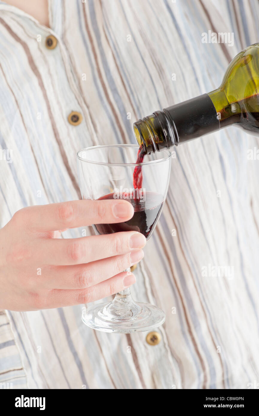 Donna versando il vino rosso in un bicchiere Foto Stock