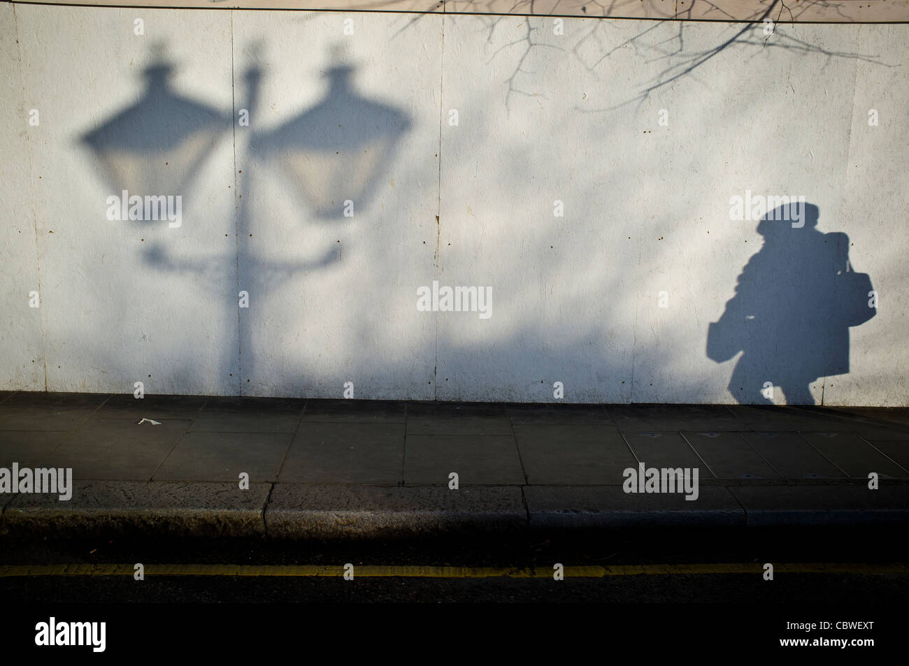 Ombra di donna che cammina verso la lampada post. Foto Stock