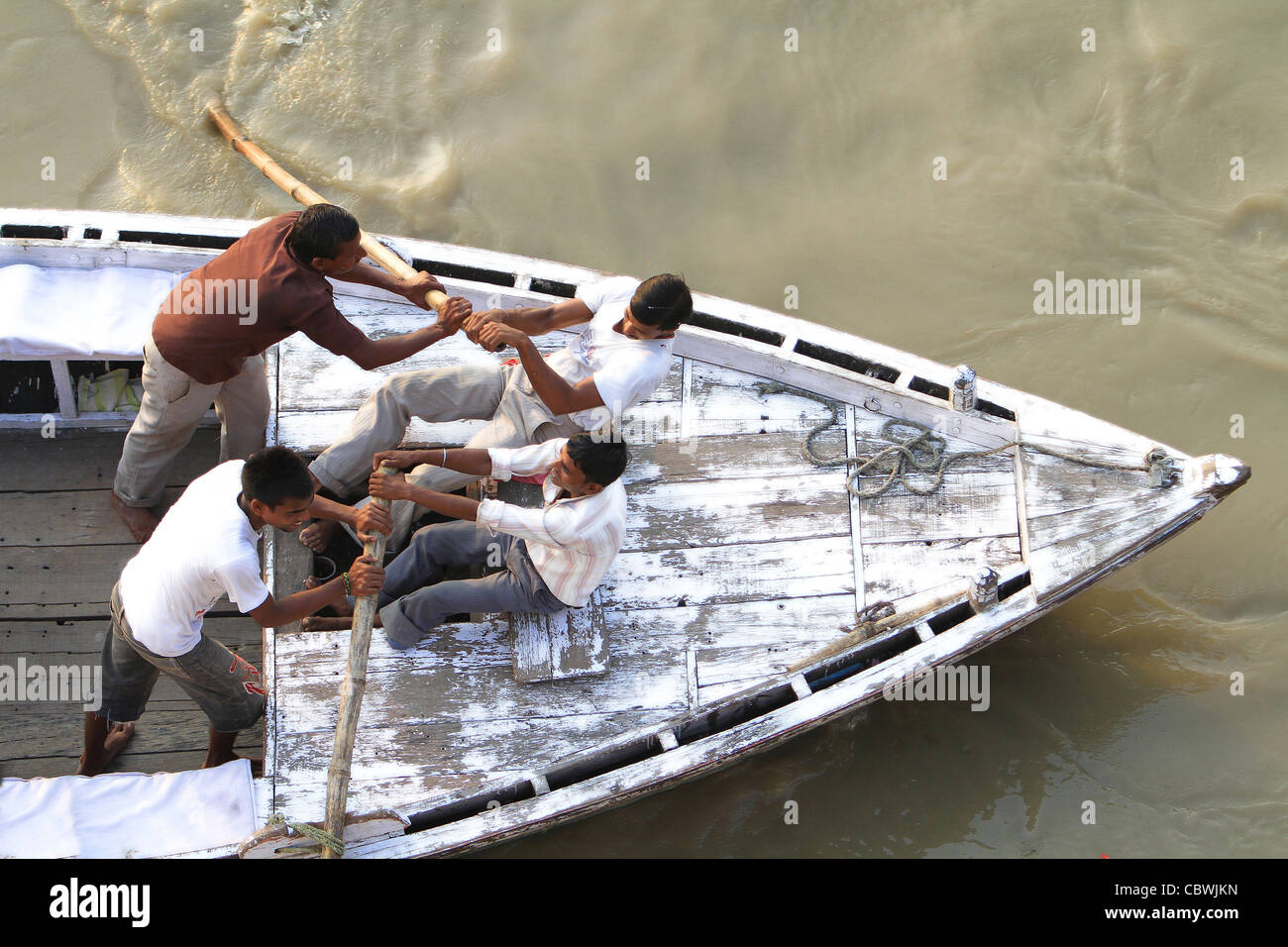 Gli uomini remare una barca di legno tradizionale sul fiume Gange. India Foto Stock