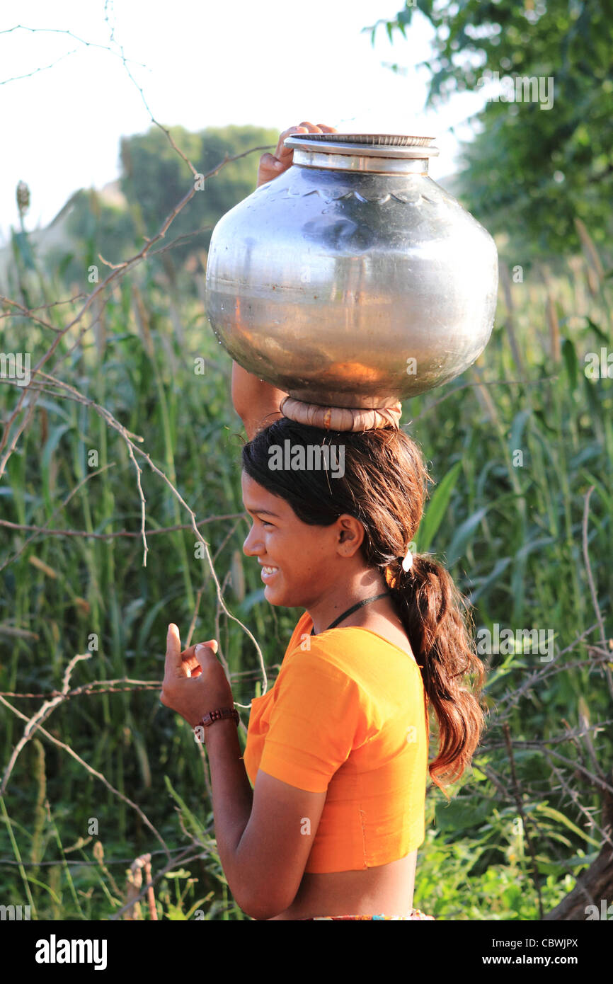 Timida ragazza sorridente portando acqua home dal bene. Il Rajasthan. India Foto Stock