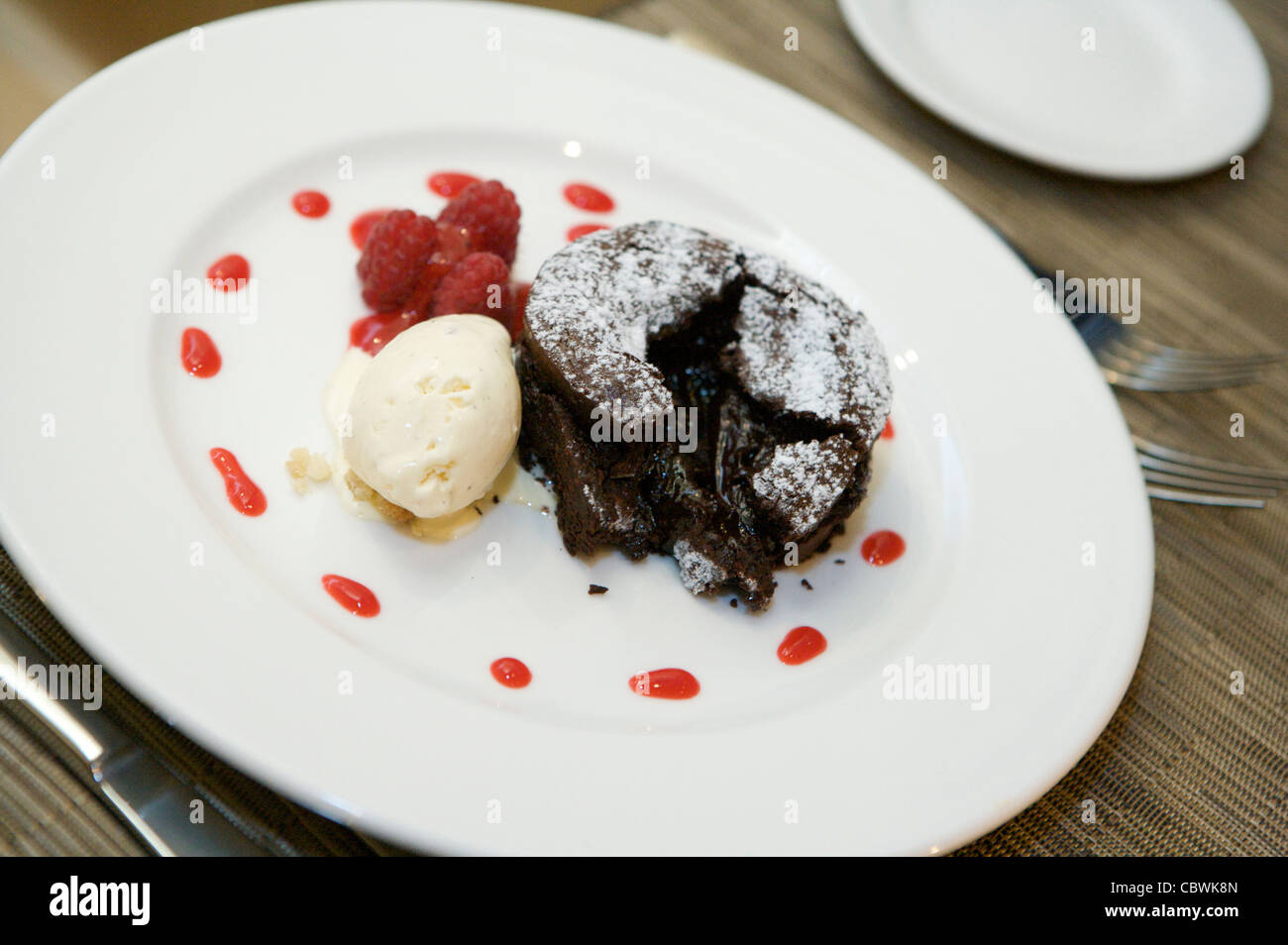 Dolce al cioccolato con gelato alla vaniglia e concentrato di lamponi Foto Stock