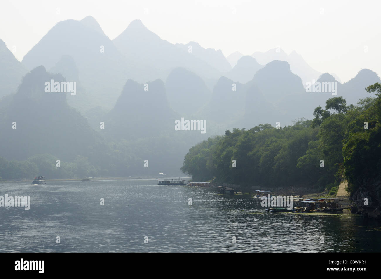 Chiatte gommoni e barche di crociera sul Fiume Li Guangxi Cina con cupola del carso montagne nella foschia Foto Stock