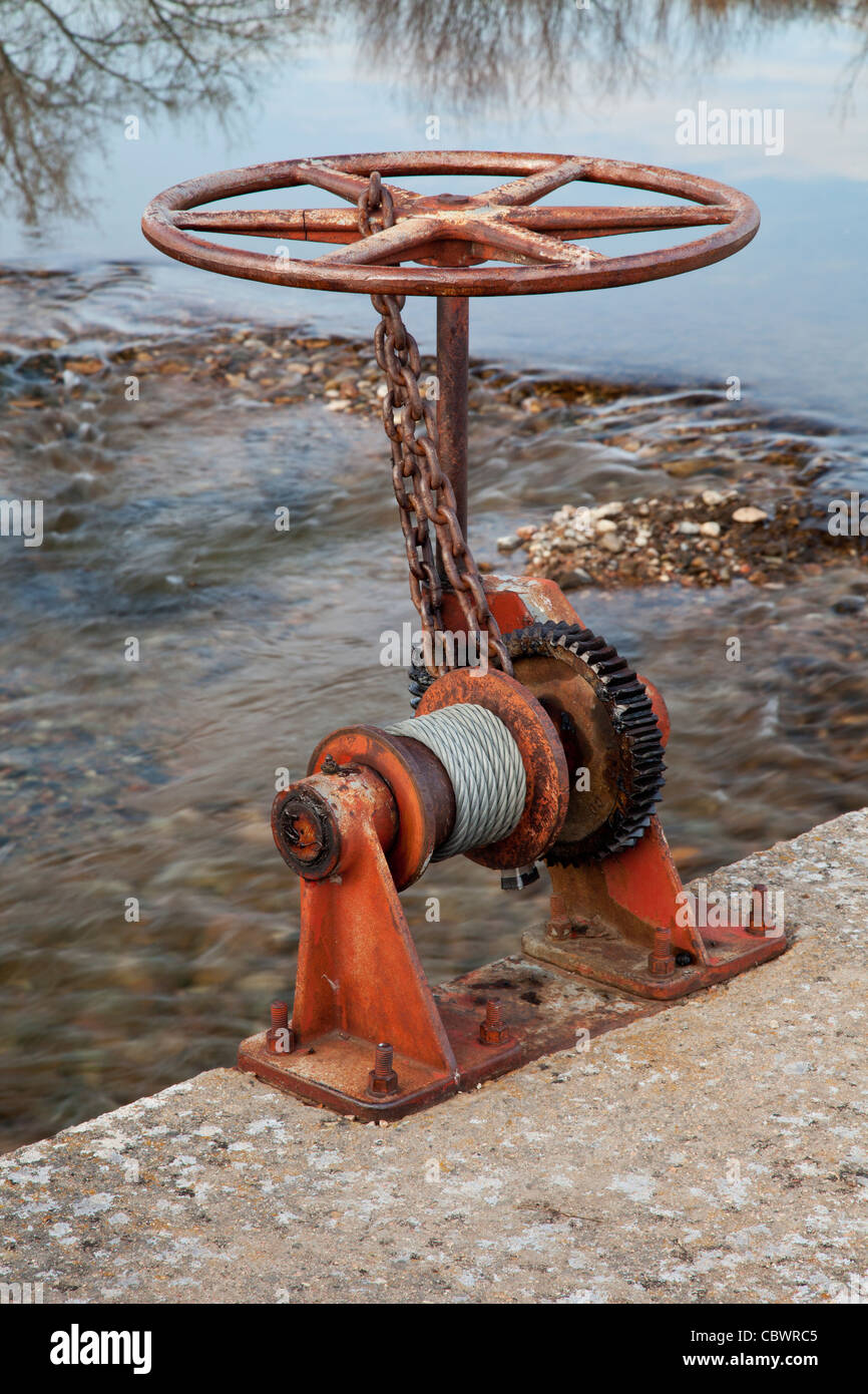 Il verricello per il sollevamento il Fosso di Irrigazione cancello con un fiume in background Foto Stock