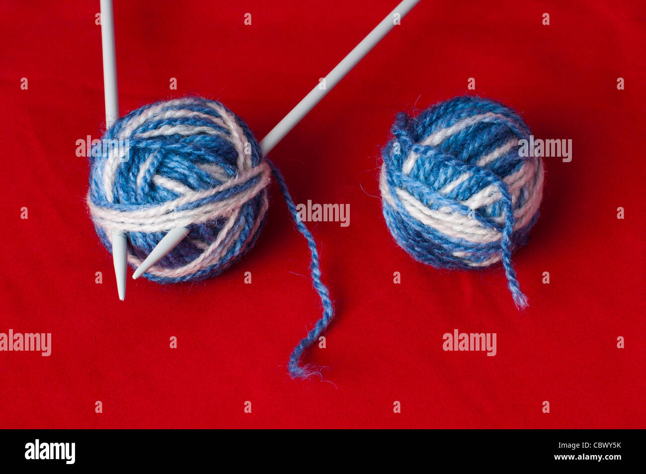 Palla di filati per maglieria e spiedini. Bianco e Blu sfere a colori su sfondo rosso Foto Stock
