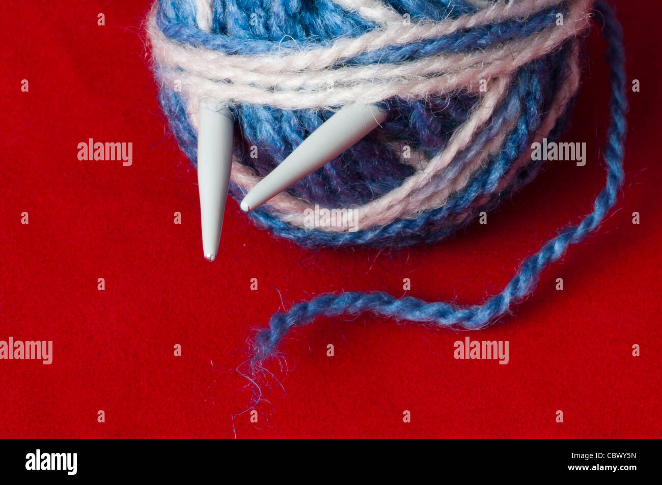 Palla di filati per maglieria e spiedini. Bianco e Blu sfere a colori su sfondo rosso Foto Stock