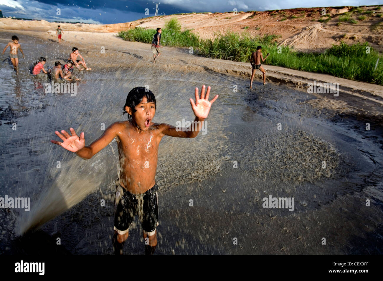 Ragazzo avente una doccia in un tubo rotto in Chacarita bidonville, Asuncion Paraguay Foto Stock