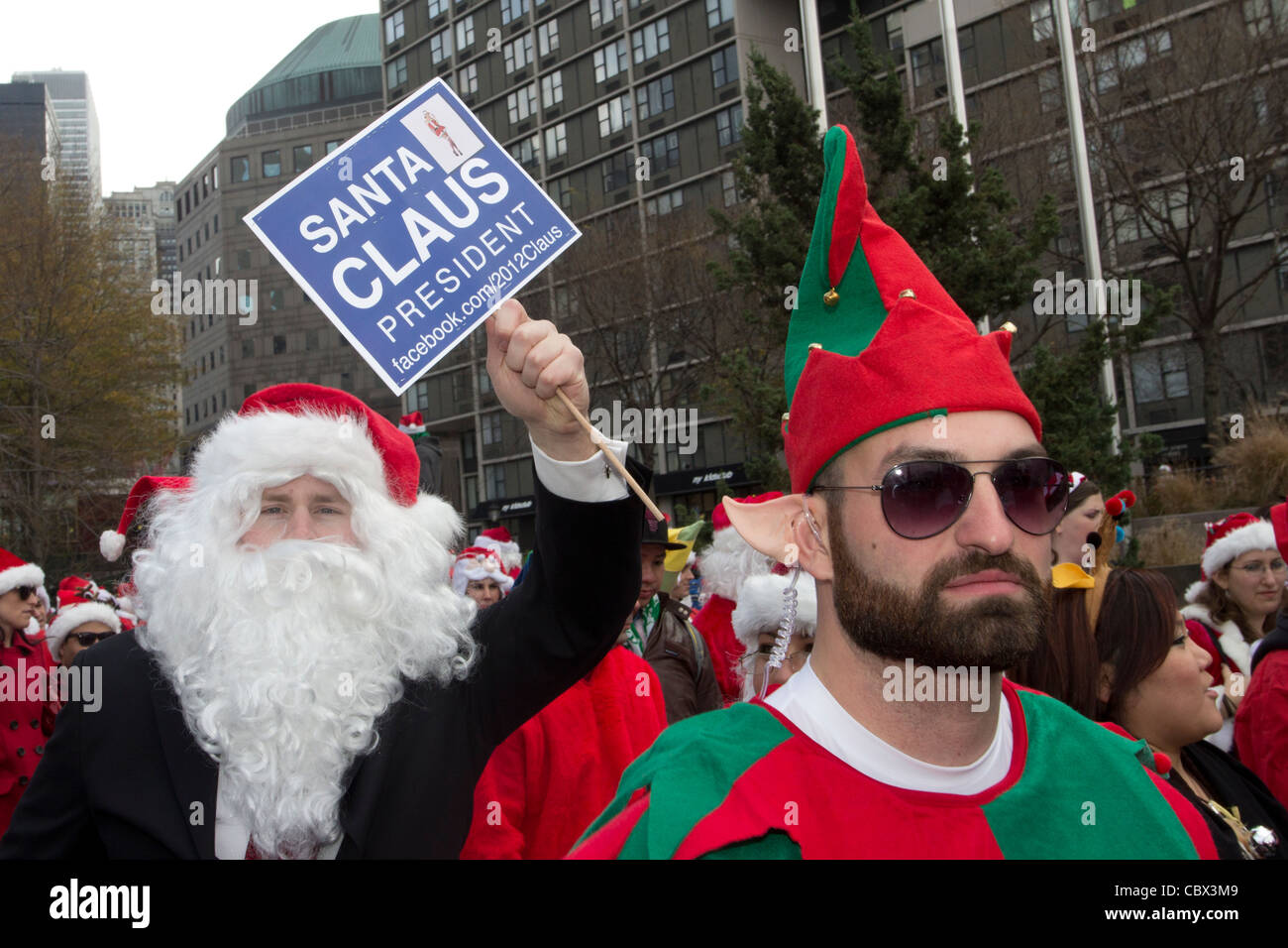 Una Santa tenendo un Babbo Natale per presidente segno a Santacon 2011 presso il World Financial Center di New York City Foto Stock