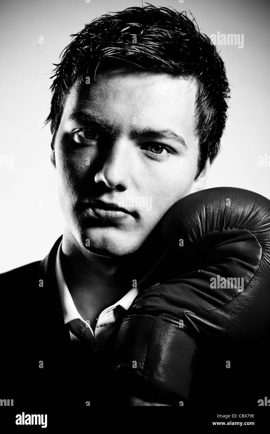 Imprenditore indossa guantoni da pugilato, su sfondo grigio Foto Stock