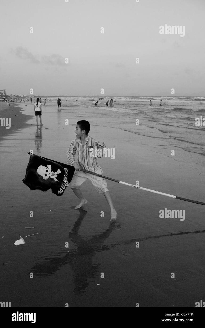 Vungtau, Vietnam. Ragazzo giocando sulla spiaggia con un indicatore utilizzato per gli avvisi come la presenza degli squali o correnti pericolose. Foto Stock