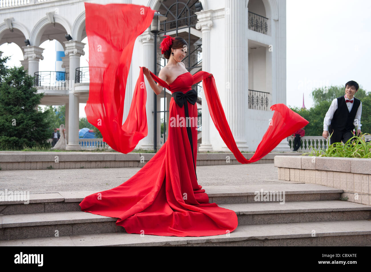 Beijing Chaoyang Park. Lavoratore che trasportano rifiuti passando un wedding photo shoot. Foto Stock