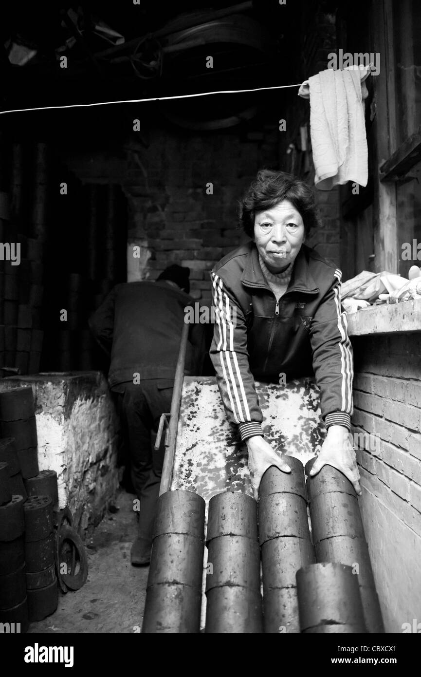 Di Pingyao, Cina. Giovane offrendo bricchette di carbone, utilizzato per il riscaldamento e la cottura dei cibi, a una famiglia. Foto Stock