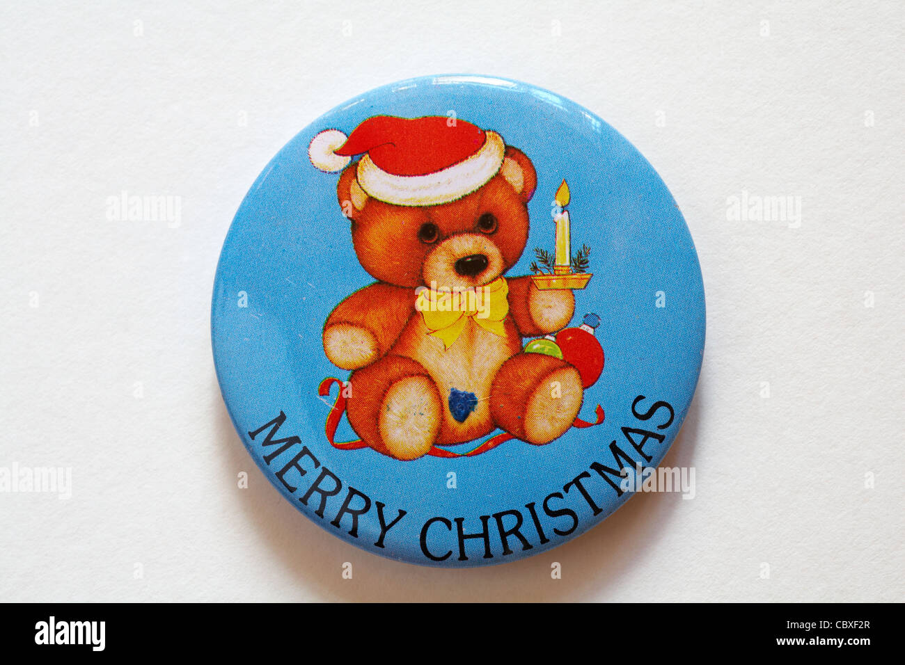 Buon Natale il badge con orsacchiotto di peluche che indossa Santa Claus hat e tenere candela isolati su sfondo bianco Foto Stock