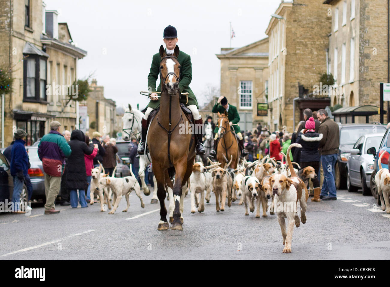 Fox Hounds essendo portano attraverso il villaggio di Chipping Norton dal maestro di caccia su un cavallo per il boxing day soddisfare Foto Stock