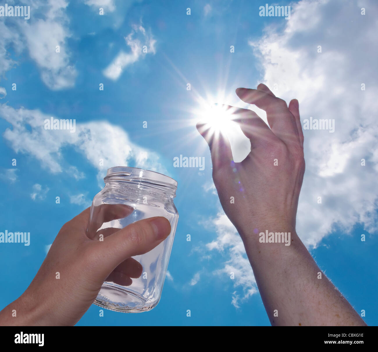 Mano tenta di mettere il sole in un vasetto di vetro Foto Stock