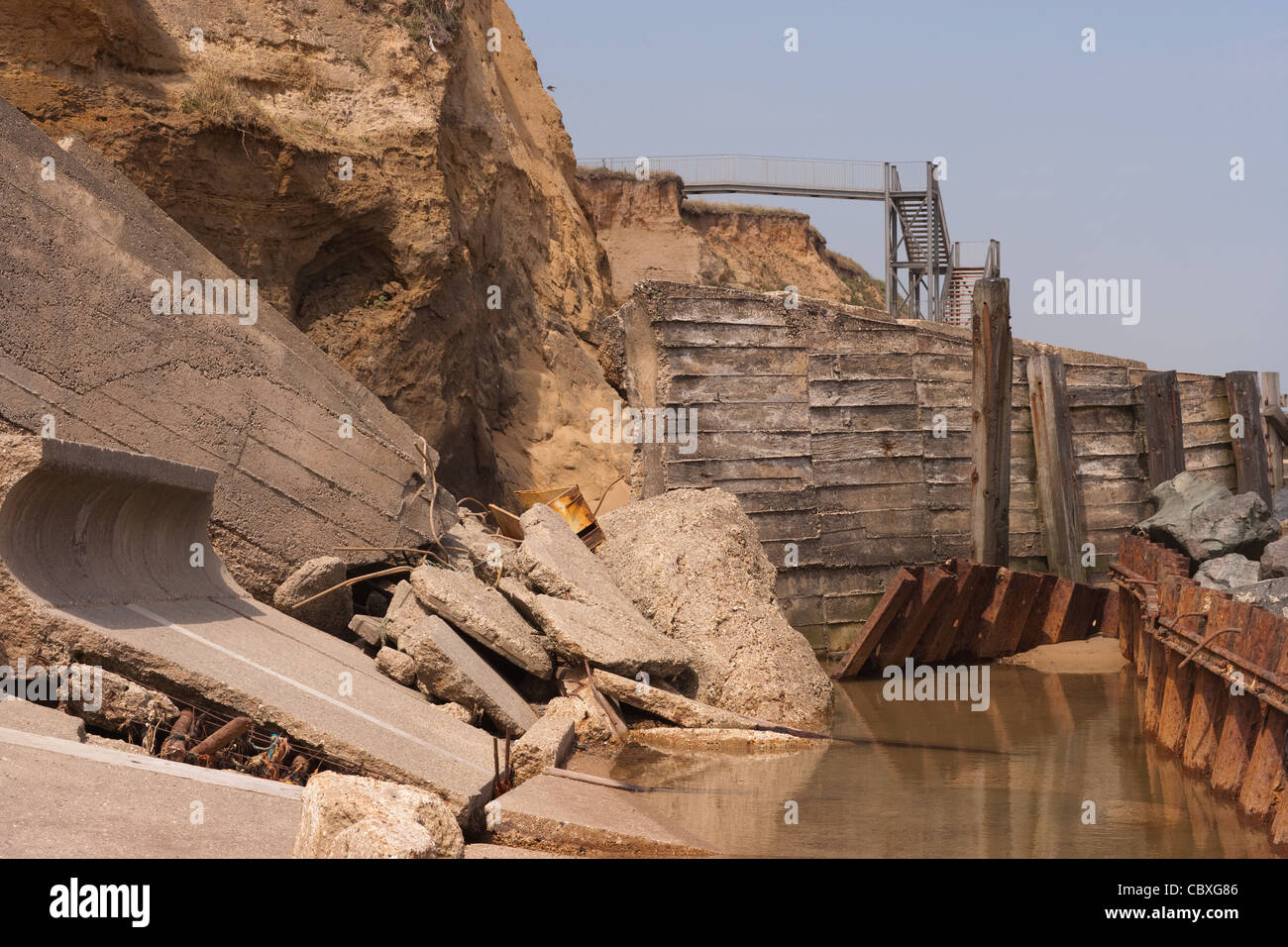 Happisburgh litorale nord di Norfolk, East Anglia. Erosione delle scogliere dal Mare del Nord e mare demolitori della difesa, pennelli, rocce. Foto Stock