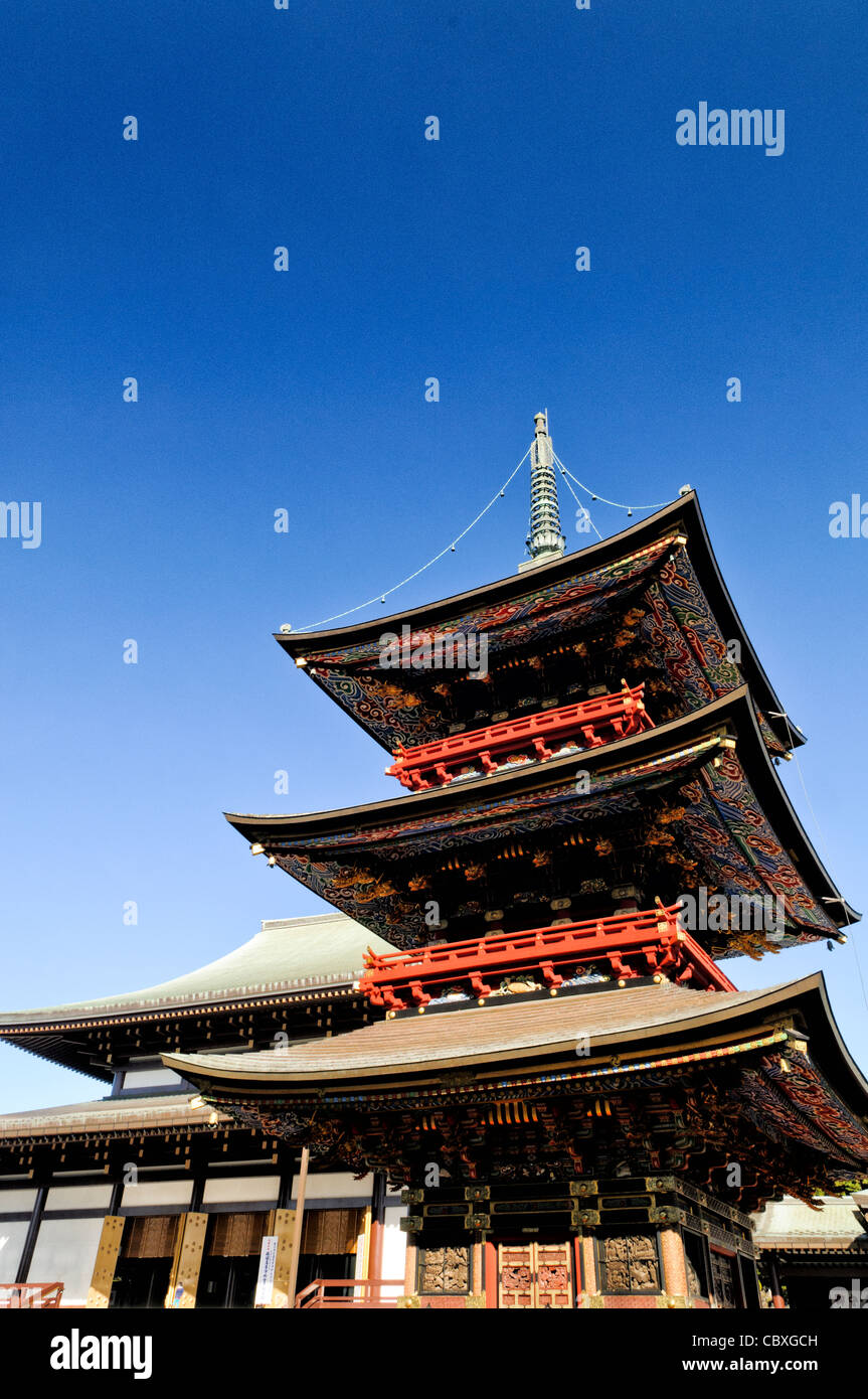 Tempio Naritasan Shinshoji Pagoda a tre piani Narita Giappone // NARITA, Giappone - travi ornati della Pagoda a tre piani del tempio Naritasan Shinshoji mostrano colori vibranti e intricati disegni caratteristici della tradizionale architettura buddista giapponese. La pagoda alta 25 metri è stata originariamente costruita nel 1712 e rappresenta una delle strutture più significative del tempio. Il tempio Naritasan Shinshoji, fondato nel 940, è dedicato a Fudo Myoo e funge da tempio principale del ramo Chisan della setta buddista Shingon. Il complesso del tempio attrae milioni di visitatori ogni anno, p Foto Stock