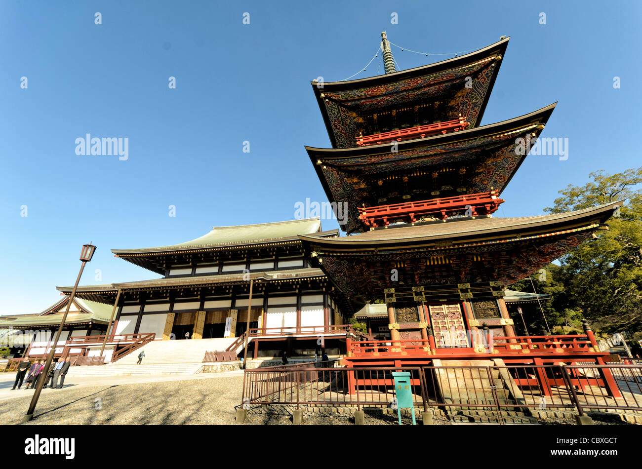 Tempio Naritasan Shinshoji Pagoda a tre piani Narita Giappone // NARITA, Giappone - travi ornati della Pagoda a tre piani del tempio Naritasan Shinshoji mostrano colori vibranti e intricati disegni caratteristici della tradizionale architettura buddista giapponese. La pagoda alta 25 metri è stata originariamente costruita nel 1712 e rappresenta una delle strutture più significative del tempio. Il tempio Naritasan Shinshoji, fondato nel 940, è dedicato a Fudo Myoo e funge da tempio principale del ramo Chisan della setta buddista Shingon. Il complesso del tempio attrae milioni di visitatori ogni anno, p Foto Stock