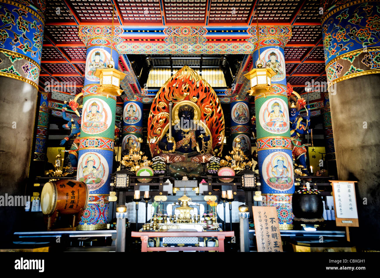 Statua di Fudo Myoo Tempio Naritasan Shinshoji Narita Giappone // NARITA, Giappone — l'imponente statua di Fudō myōō (Re della saggezza inamovibile) si trova all'interno del Daitou (grande Pagoda) al tempio Naritasan Shinshoji. Questa figura centrale di culto rappresenta una delle divinità più importanti del buddhismo Shingon, che funge da protettore che rimuove gli ostacoli e distrugge il male. La statua è ospitata all'interno della pagoda alta 58 metri, che è stata costruita nel 1984 come parte della moderna espansione del complesso del tempio. Fudō myōō è tipicamente raffigurato con un'espressione feroce e circondato da fiamme, simboleggiando il bu Foto Stock