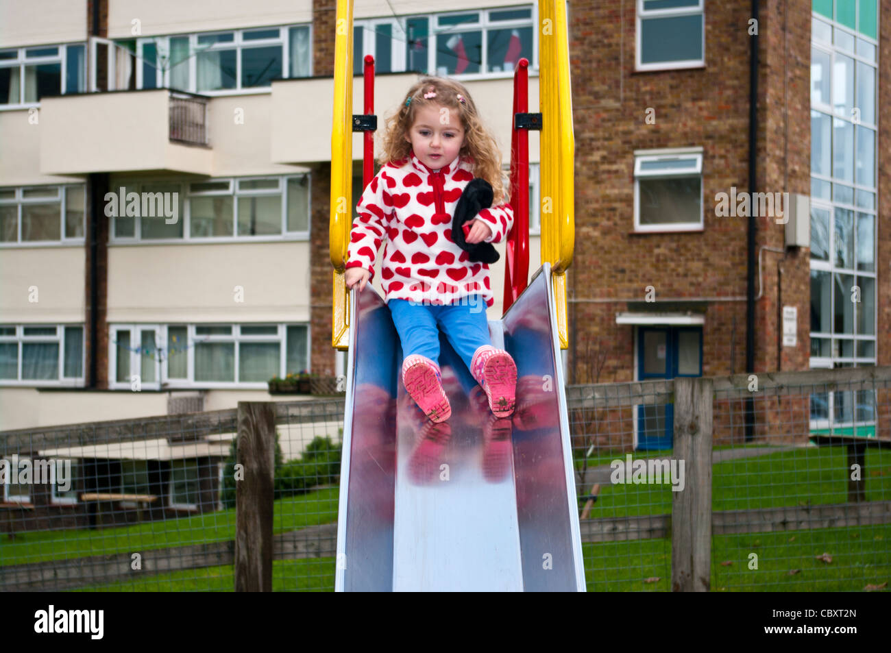 Bambino di 3 anni ragazza Neonato Bimbo giocando lo scorrimento verso il basso una diapositiva in un parco giochi per i bambini Foto Stock