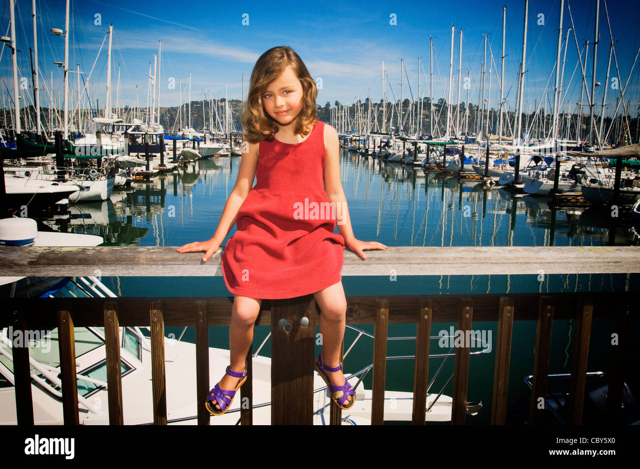 Giovane ragazza seduta al molo in un giorno di estate Foto Stock