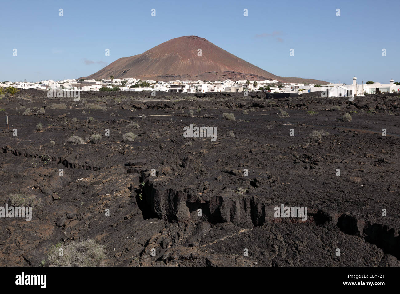 Tipico paesaggio di Lanzarote, lava, villaggio e vulcano Foto Stock