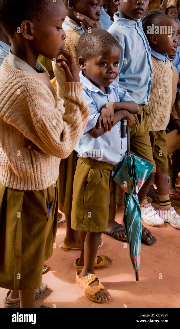 Felice fiducioso cercando la pupilla con ombrellone presso una scuola in Voi il Kenya meridionale ad ascoltare un discorso Foto Stock