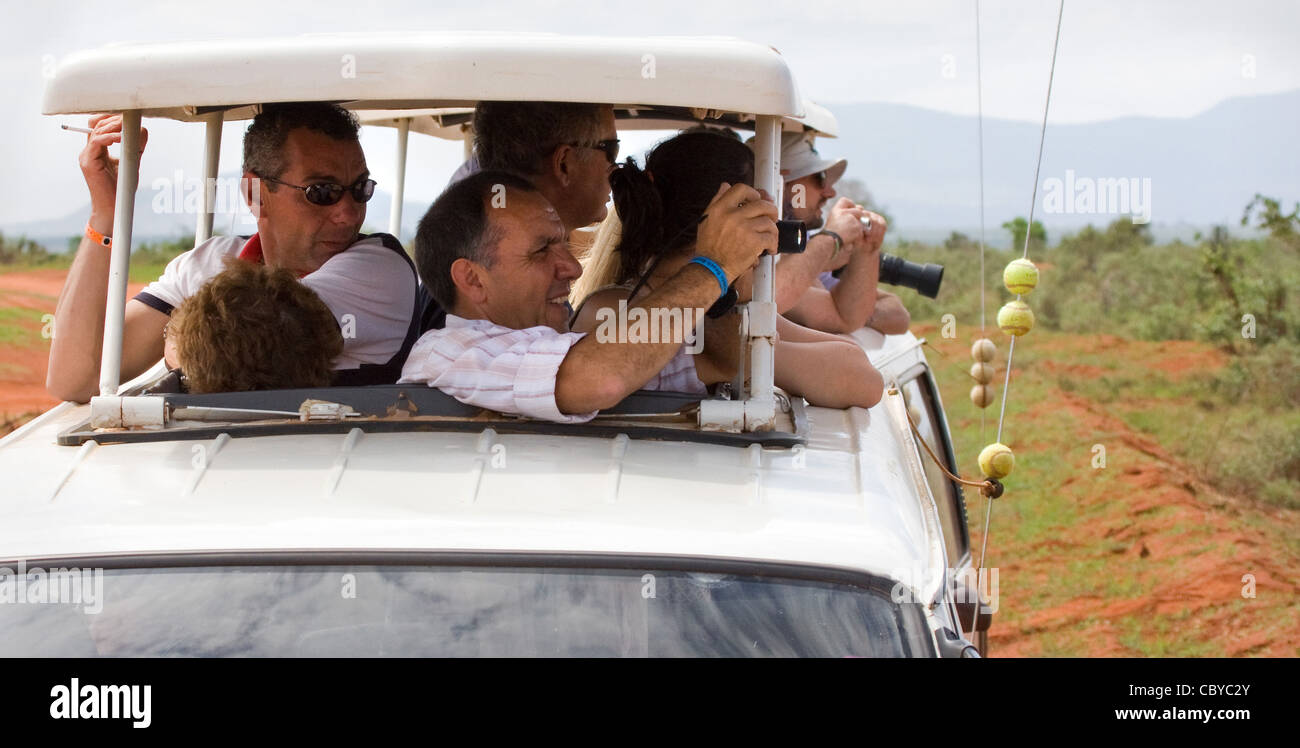 Un gruppo di turisti italiani hanno affollato un safari ceppo del veicolo a prendere le fotografie degli animali al Parco Nazionale Tsavo Kenya Foto Stock
