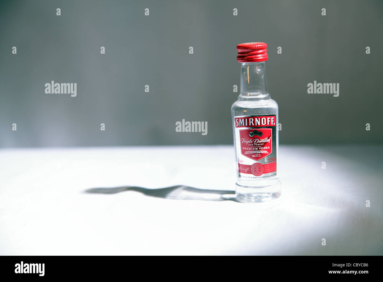 Bottiglia in miniatura di Smirnoff vodka in loco la luce sul tavolo bianco Foto Stock