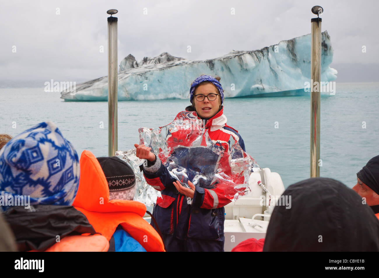 Una guida spiega il ghiaccio del ghiacciaio a bordo di un tour della laguna glaciale, Islanda. Foto Stock