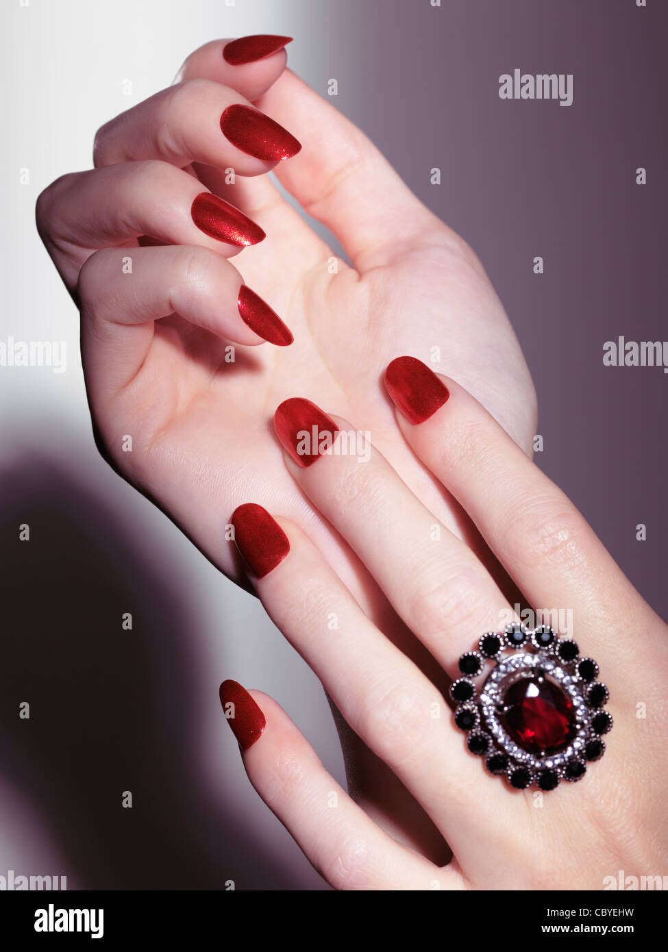 Licenza disponibile al sito MaximImages.com primo piano di mani donna con smalto rosso lucido e un anello di pietra rossa Foto Stock