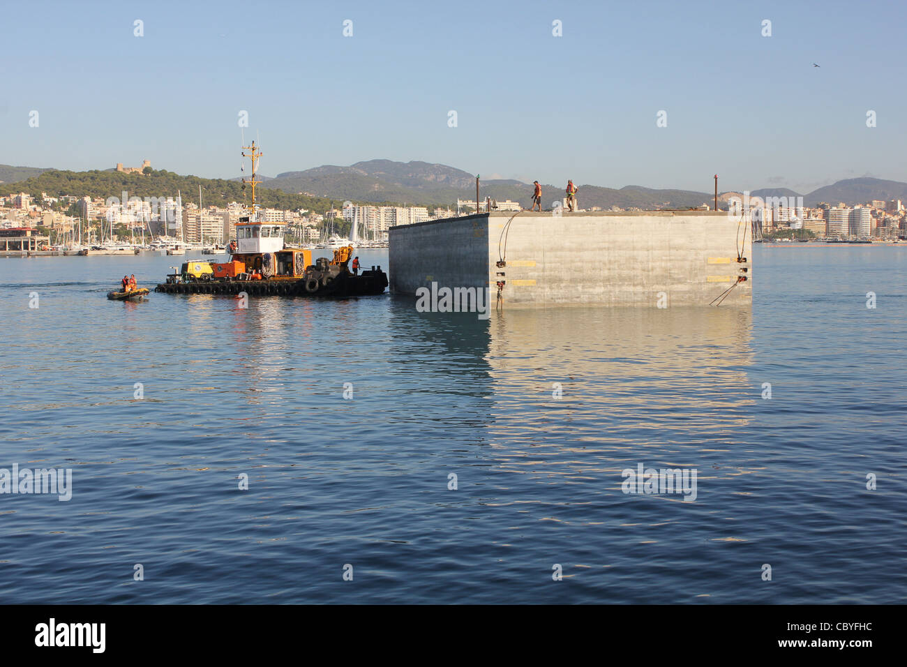 Grandi blocchi di cemento ( destinato alla porta estensione funziona ) essendo manoevered su tempory berth, porto di Palma de Mallorca Foto Stock