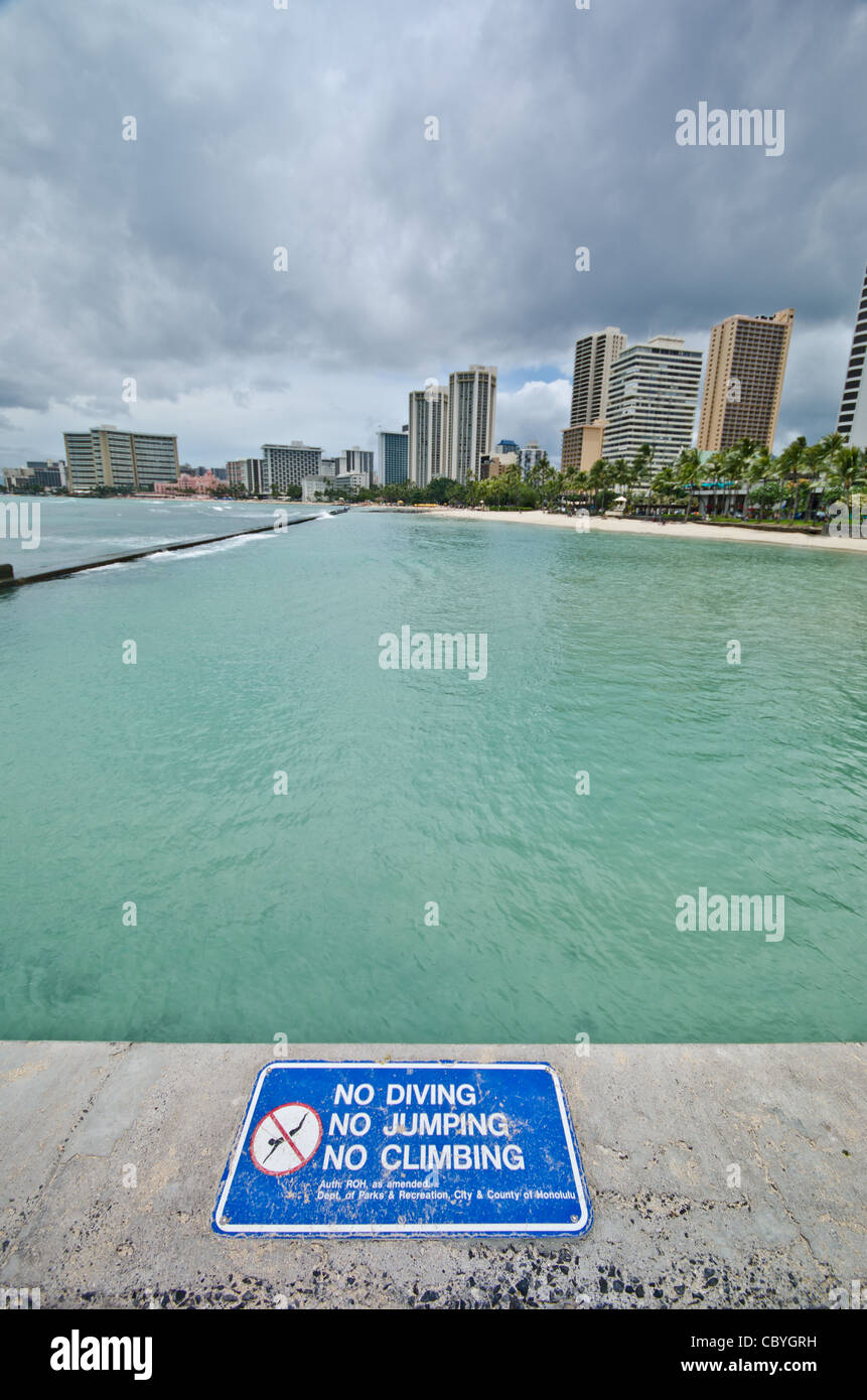 Una vista della baia di Waikiki, Honolulu Oahu, Hawaii, con una placca in vista che gli stati 'No immersioni subacquee, No Jumping, no Arrampicata' Foto Stock
