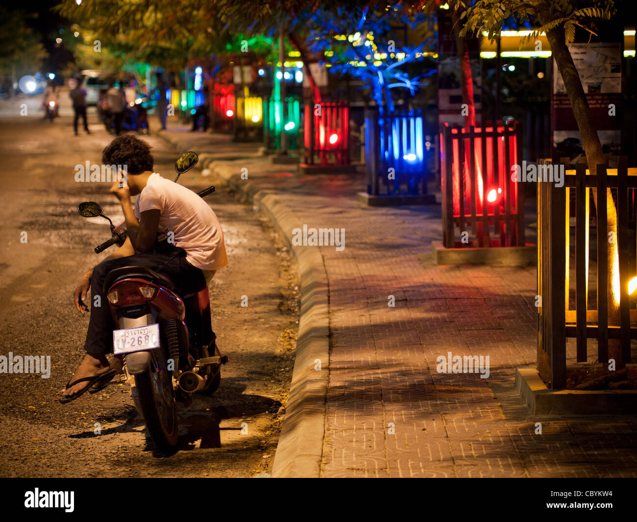 Un ragazzo si siede sulla sua moto in un toccante scena di strada in Siem Reap, Cambogia. Foto Stock