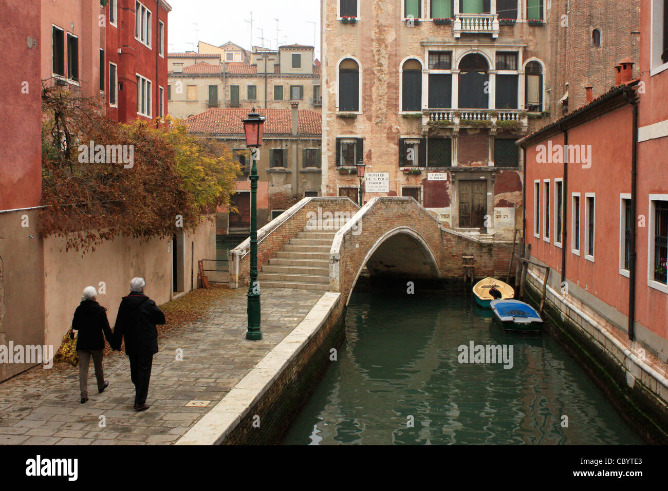 Una coppia di anziani camminare mano nella mano in una strada da un canale di Venezia, Italia, Luglio 1, 2011. Foto Stock