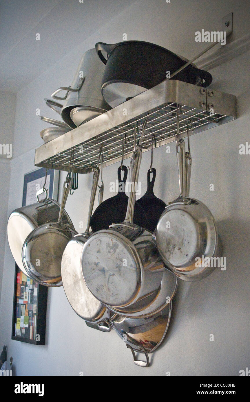 Un assortimento di cucina, pentole, padelle, utensili, su rack da parete, il ripiano Foto Stock
