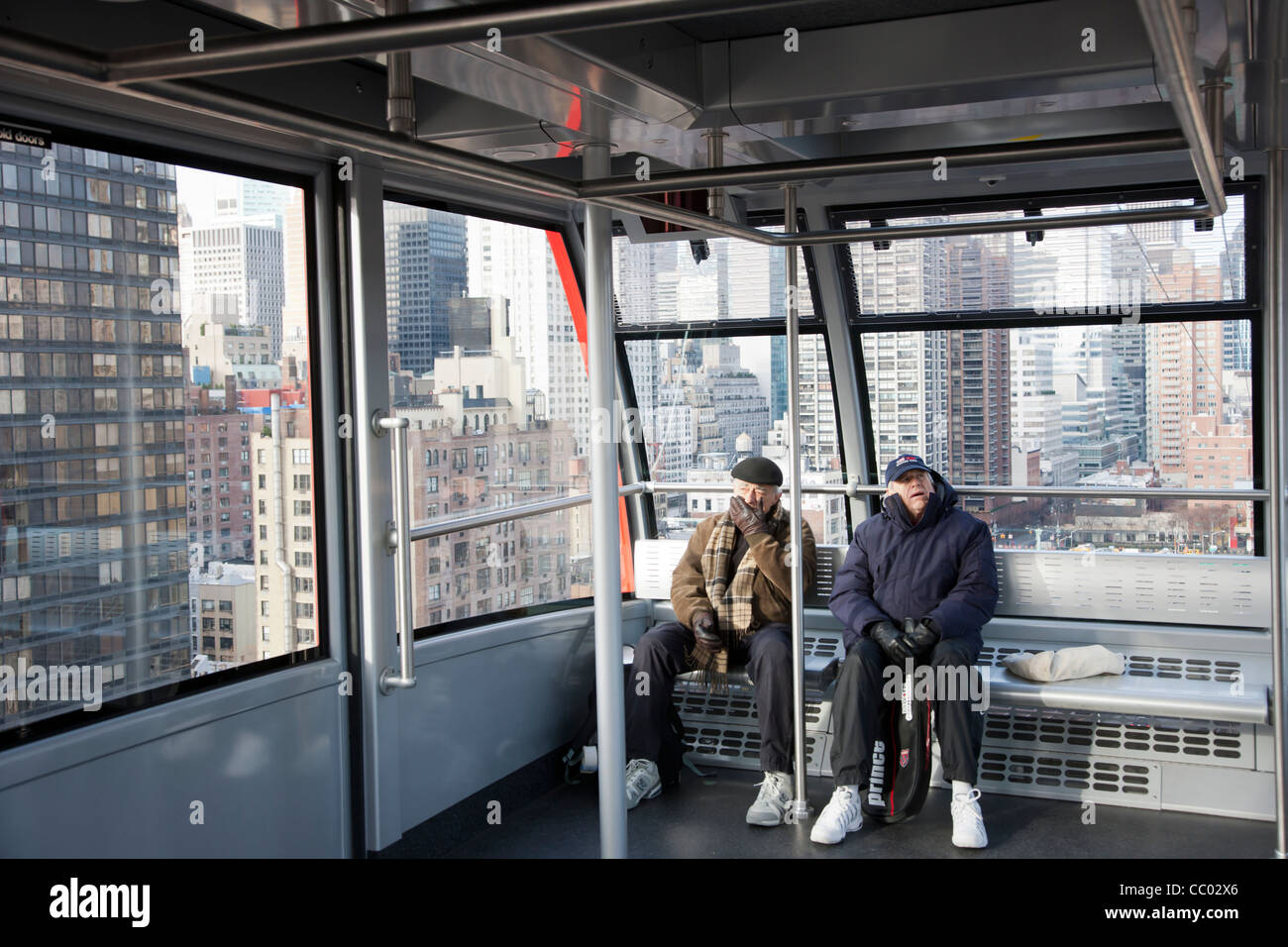 Due passeggeri a bordo del Roosevelt Island Tram diretti per il Roosevelt Island, con la East Side di Manhattan in background Foto Stock