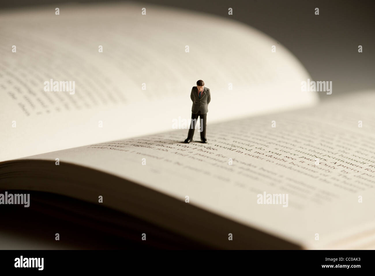 Una piccola figura di un uomo che cammina su un libro aperto - immagine concettuale per l alfabetizzazione e la lettura Foto Stock