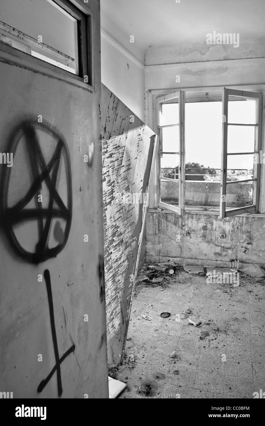 Simboli satanici graffiti sulla porta di una casa abbandonata. In bianco e nero. Foto Stock