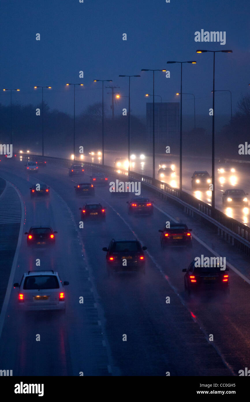 Auto e traffico sul bagnato piove di sera su autostrada del Regno Unito, guida in pericolose condizioni invernali. Foto Stock