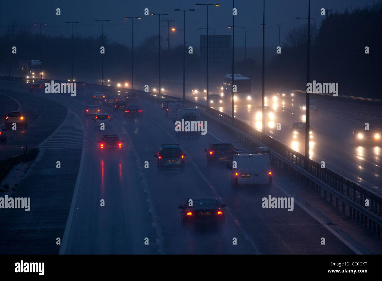 Auto e traffico sul bagnato piove di sera su autostrada del regno unito.La Guida in pericolose condizioni invernali. Foto Stock