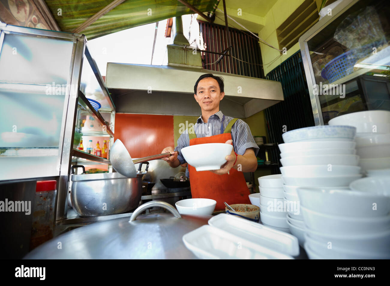 Lo chef prepara tradizionali asiatici street food e lavorare nella cucina del ristorante. Sagoma orizzontale, vista frontale Foto Stock