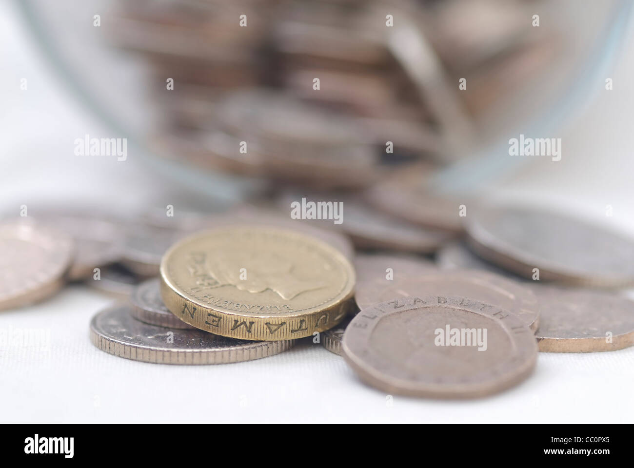 Eventuali fuoriuscite di monete da un barattolo di vetro, concentrarsi su £1 moneta. Sterlina. Foto Stock