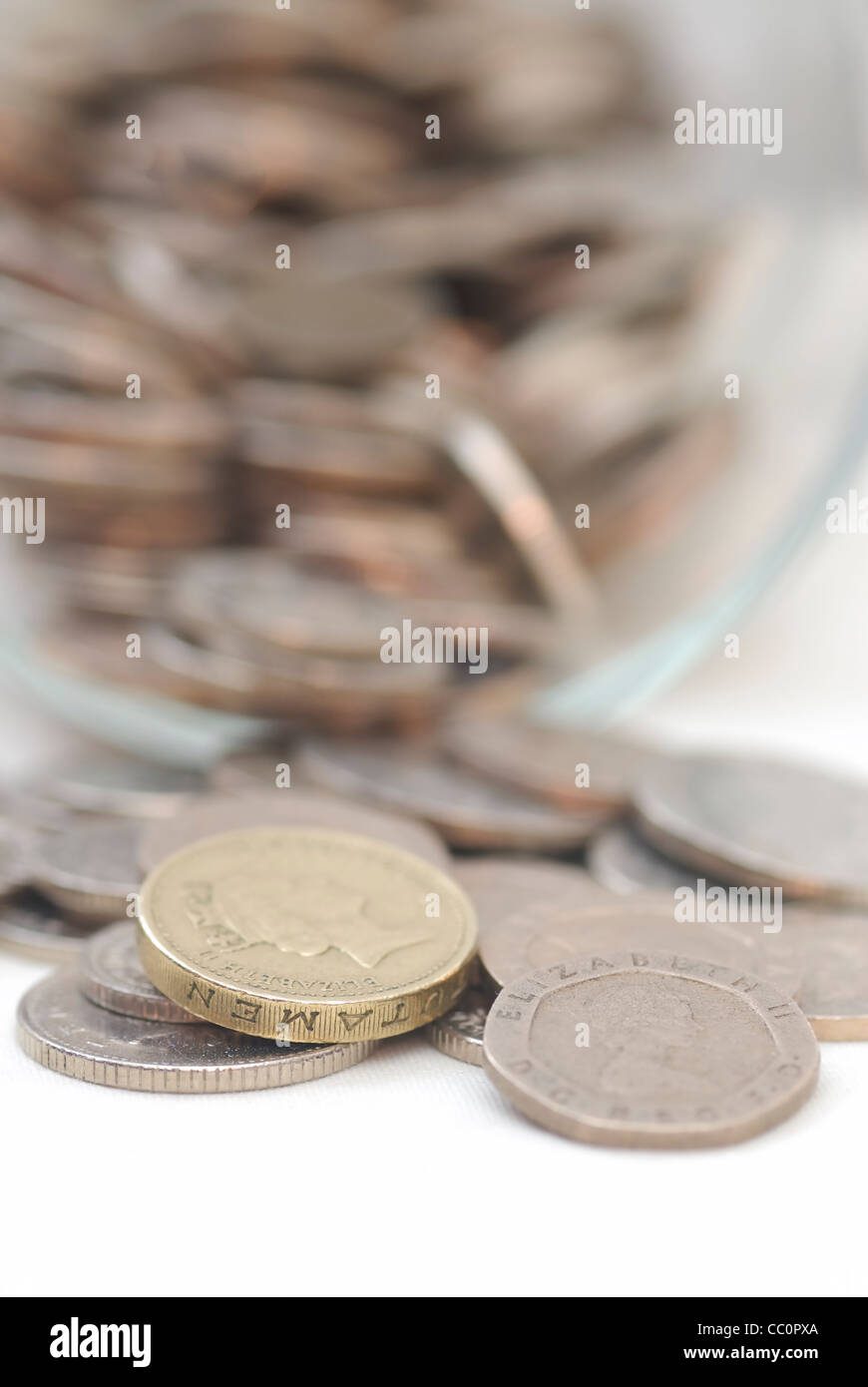 Eventuali fuoriuscite di monete da un barattolo di vetro, concentrarsi su £1 moneta. Sterlina. Foto Stock