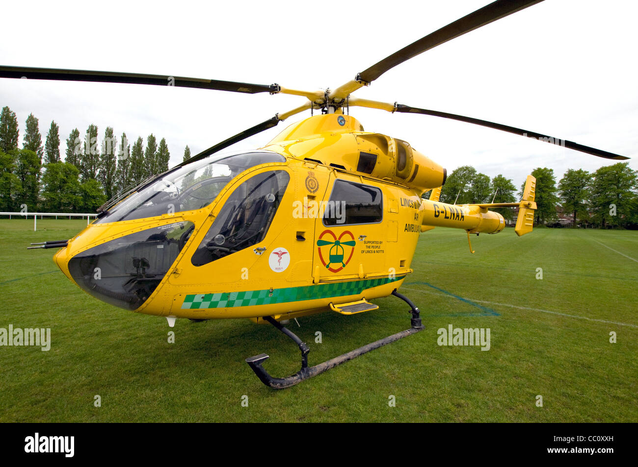 Nottinghamshire Air Ambulance elicotteri sbarcati su un campo di calcio, alberi in background Foto Stock