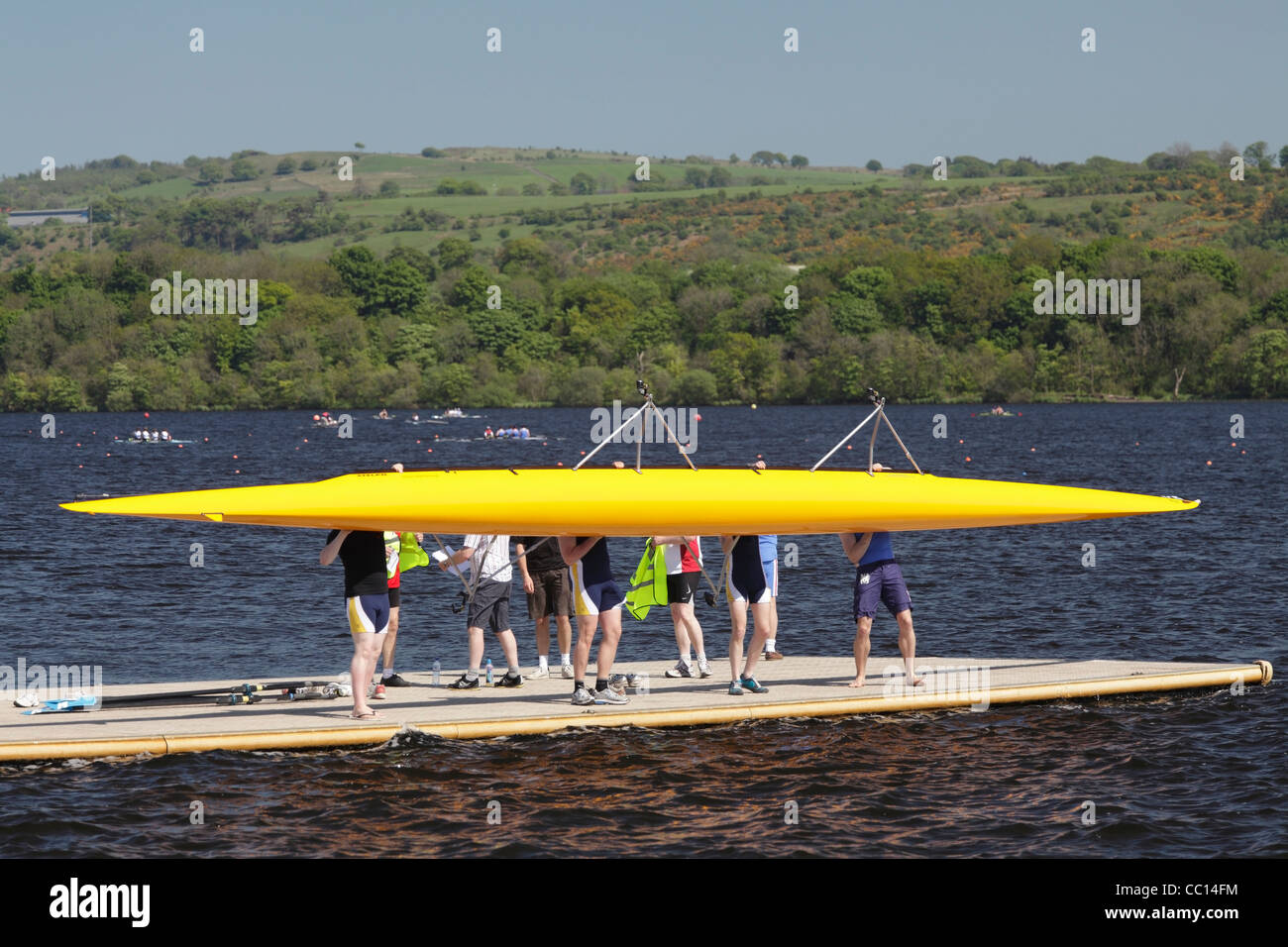 La squadra di canottaggio su un molo che solleva un doppio scull per metterlo in acqua, Regno Unito Foto Stock