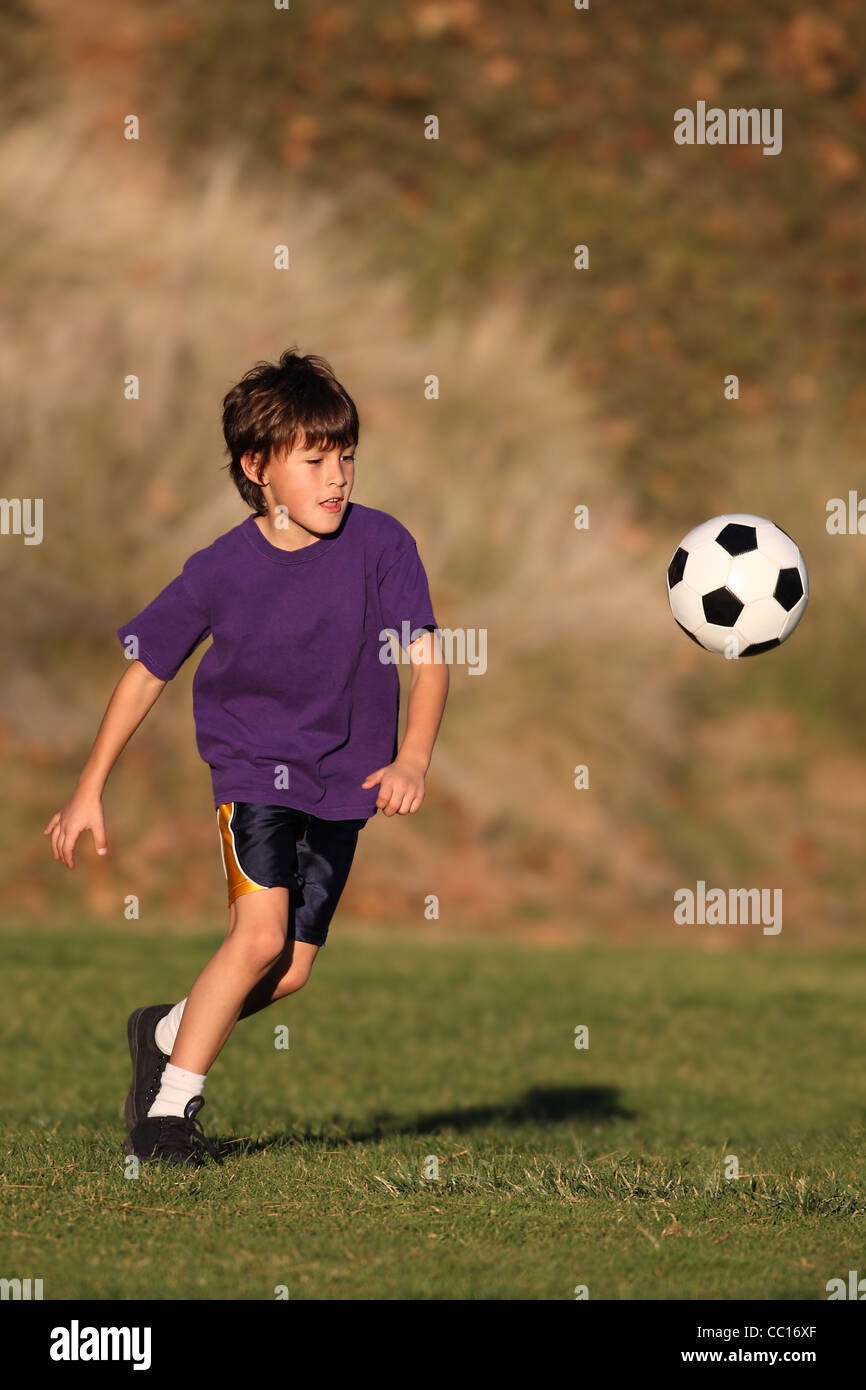 Ragazzo giocando con il pallone da calcio in prima serata la luce solare Foto Stock