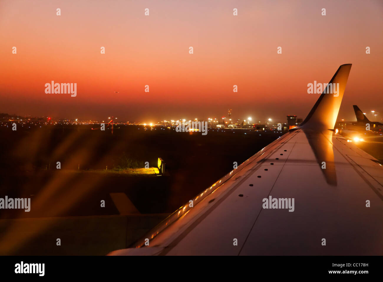 Paesaggio orizzontale mumbai airport al crepuscolo quando un aereo taxi un altro è lo sbarco. Incandescente i colori del tramonto Foto Stock